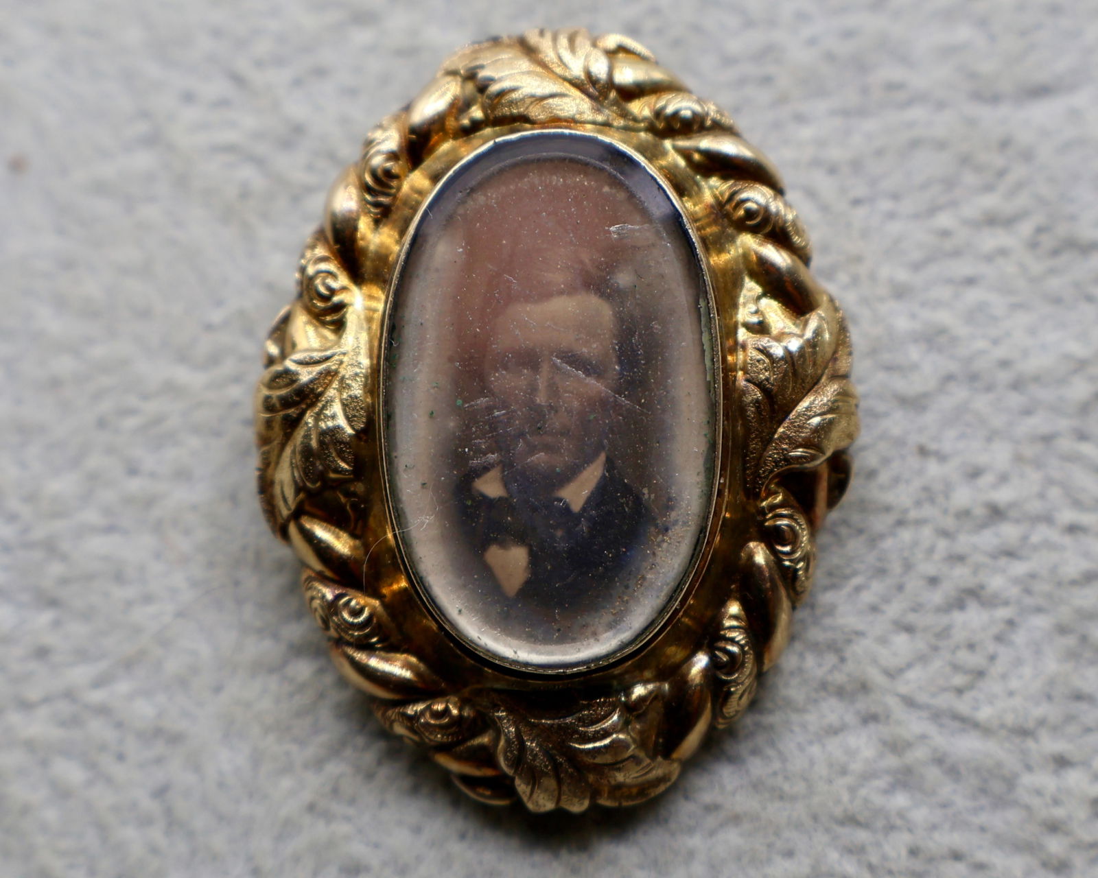 A Gold Filled Picture Ambrotype Memorial Pendant: Civil war period. A gold shelled mourning pendant with an image of a gentleman inside. The border is well crafted with a highly detailed leaf pattern.