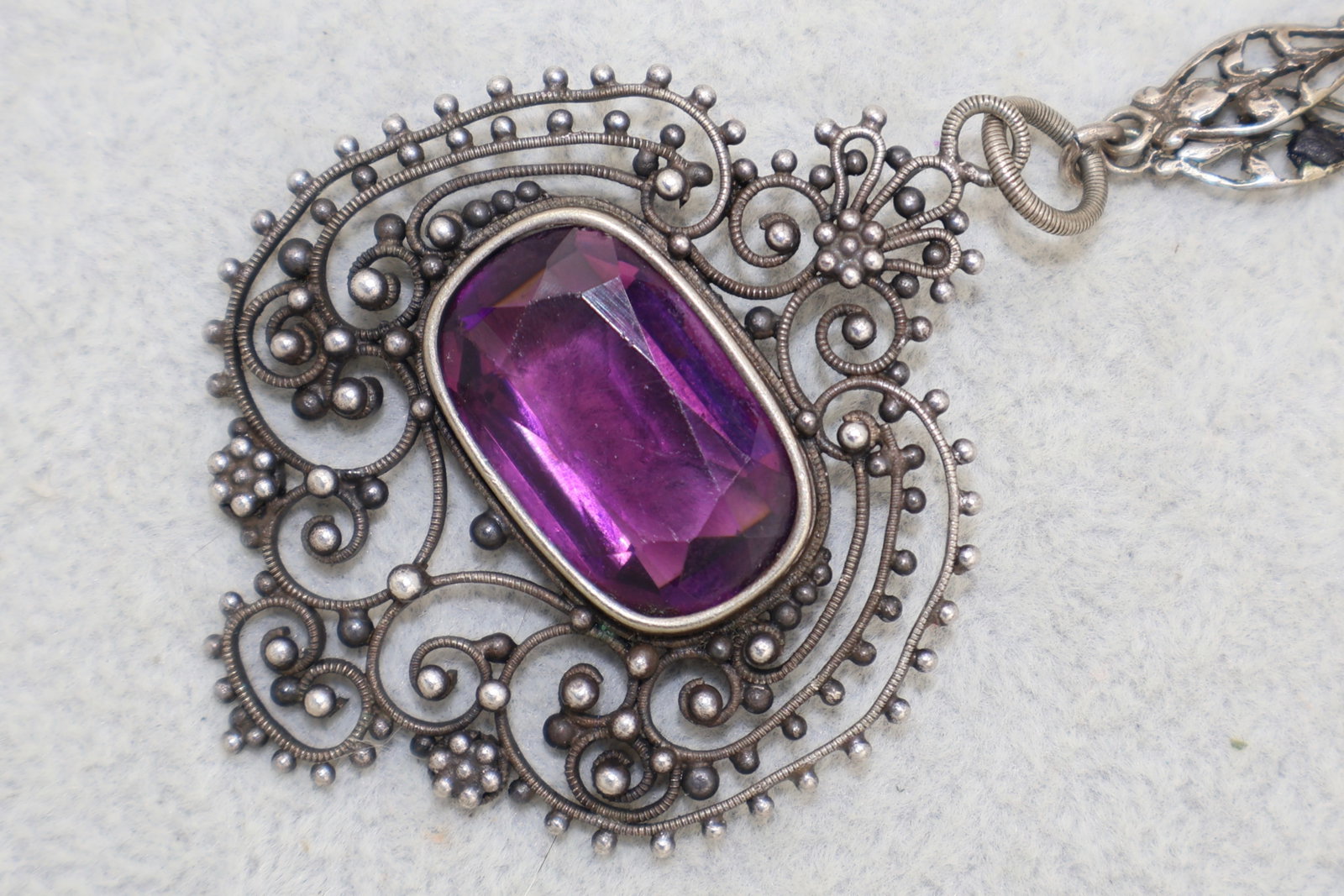 Art Deco Amethyst Glass Sterling Filigree Necklace: 1920’s-1930’s period. An elegant and very well handcrafted period necklace. Flapper style. A beautiful floral link and glass amethyst stones highlight the necklace. The center pendant has a very n