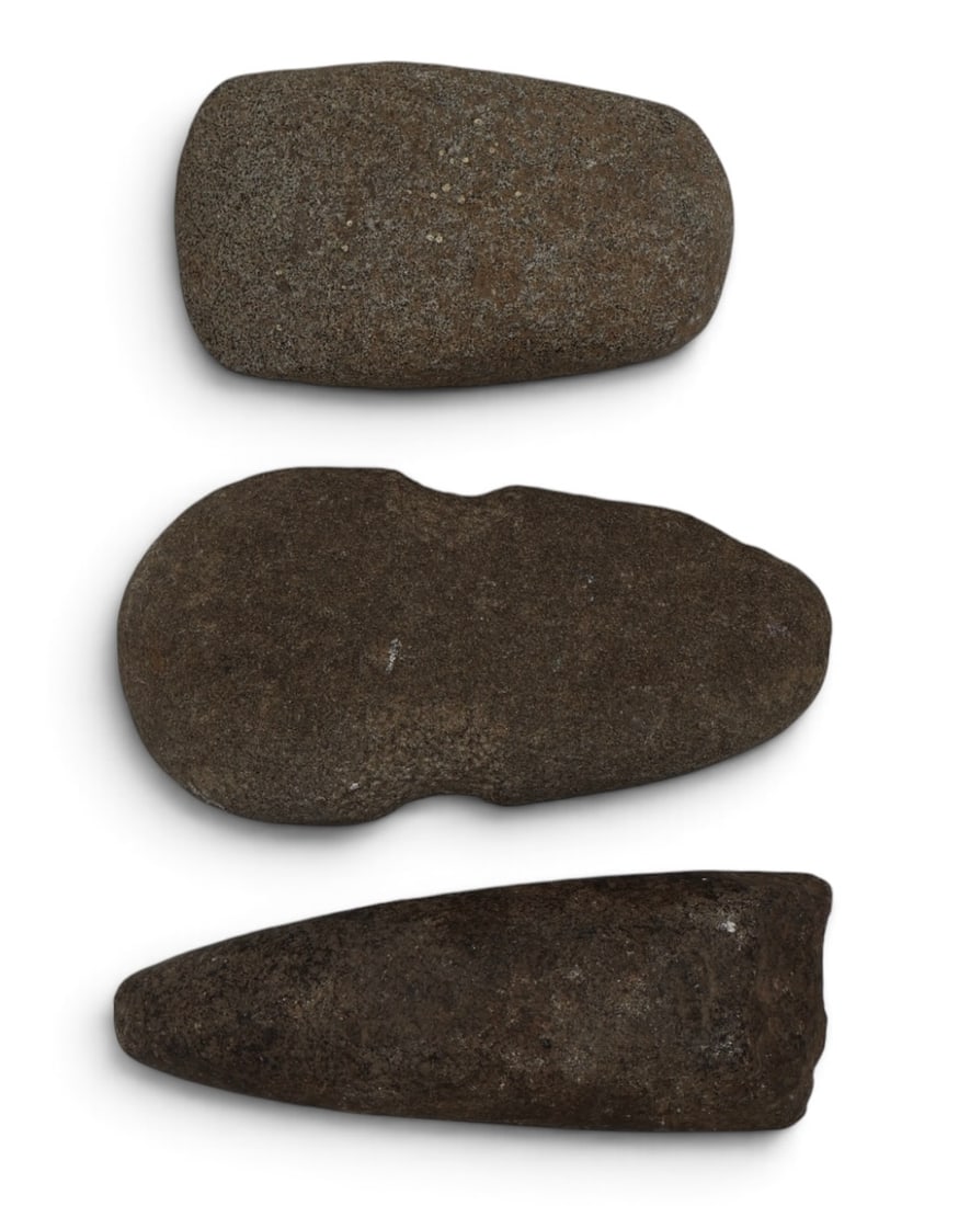 A Grouping of a Native American Stone Celt, Adze and Axe: A trip of stone artifacts from a Midwestern collection. Featuring a very nice Celt, Axe, and an Adze. All shows signs of use. Ancient. Largest is 6” x 3”.