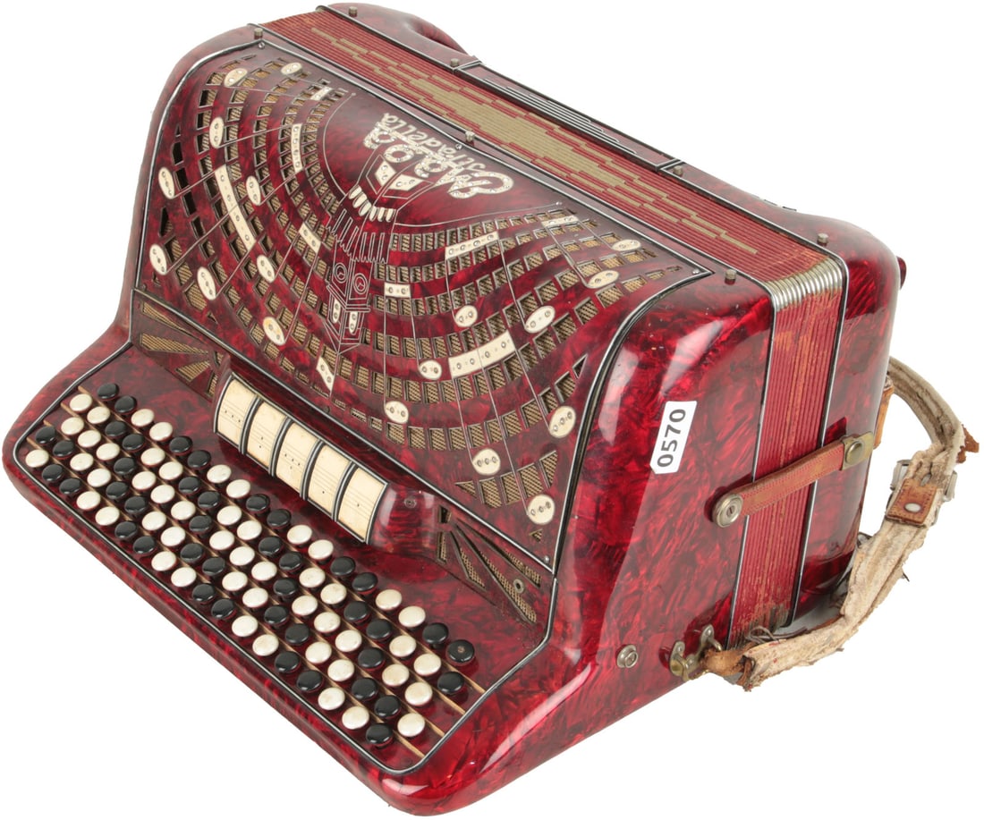 Maga Stradella Accordion: 92 treble buttons, 120 bass. 5 treble buttons, 1 bass. Red marble finish, illustrated red and white grille with jewels, with white jewelled lettering. Comes with leather strap. Made in Italy. Weight 1