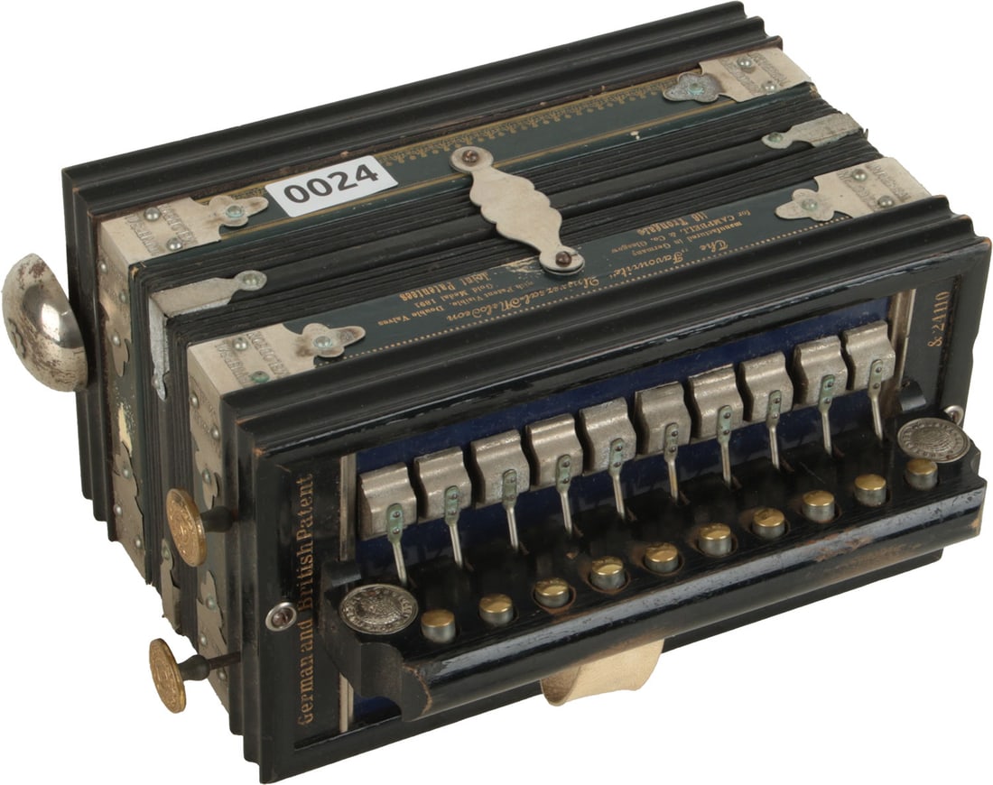 The Favourite Universal Melodeon: 10 treble buttons, 2 bass and bell. Ebony finish, green leather trim, gold lettering and metal corner caps. Made in Germany. Weight 1.6kg. No Visible Damage