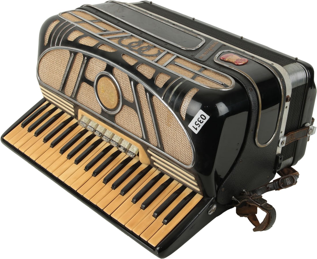 Monofonica Benigallia Accordion, Italy: 41 keys, 120 bass. Keyboard 19". 7 treble buttons, 5 bass. Black and silver finish, gold lettering, gold grille netting, silver glitter treble buttons. Comes with leather strap. Made in Italy. Weight