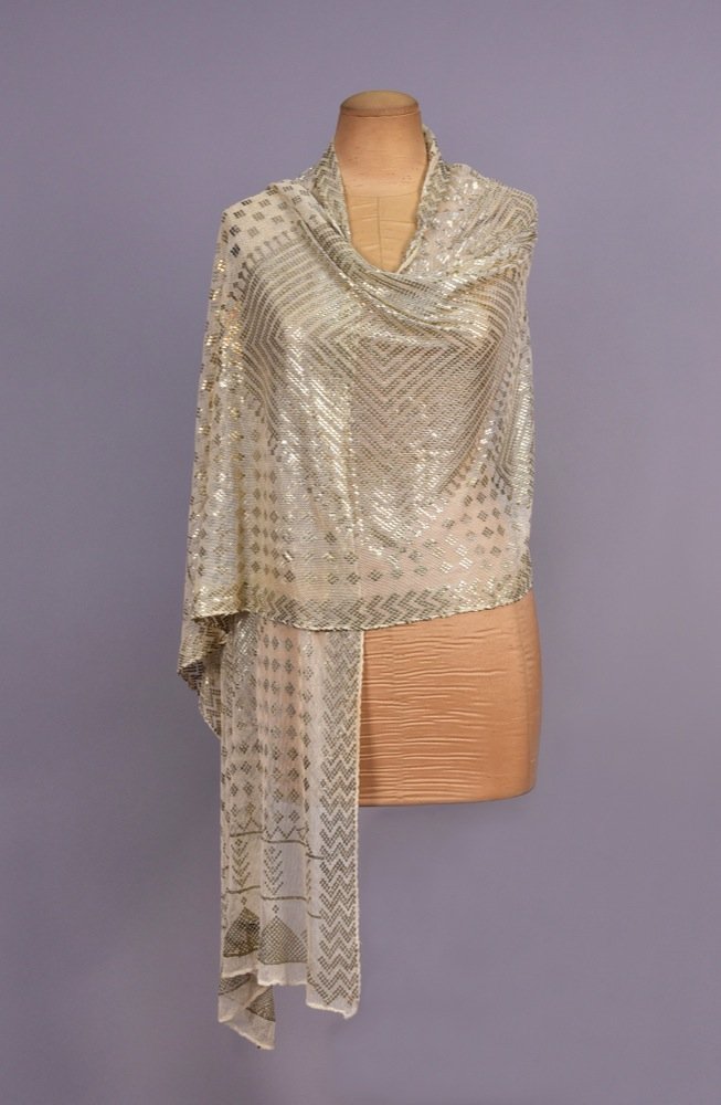 EGYPTIAN ASUIT SHAWL, 1920s.: White cotton net having hammered silver decoration of large and small diamond shapes with chevron border and end borders with trees and pyramid shapes. 25 x 85. (Minor tarnish) very good.