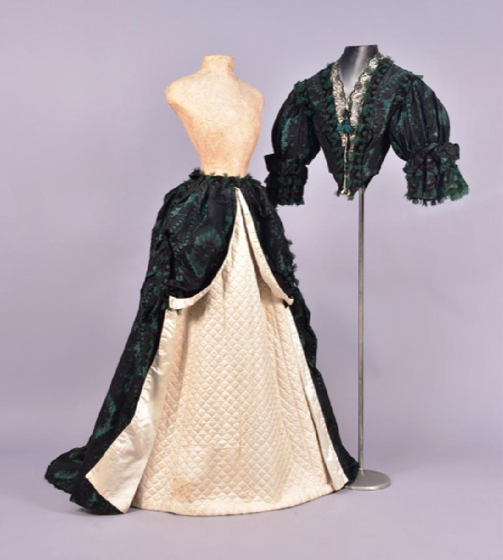 PATTERNED WEAVE and SILK BROCADE GOWN, 1860s.: 2-piece emerald green silk woven with blocks and ribs, brocaded with a black floral repeat in ribbed lozenge shapes, pointed bodice having puffed and ruffled elbow-length sleeve, lace over cream satin