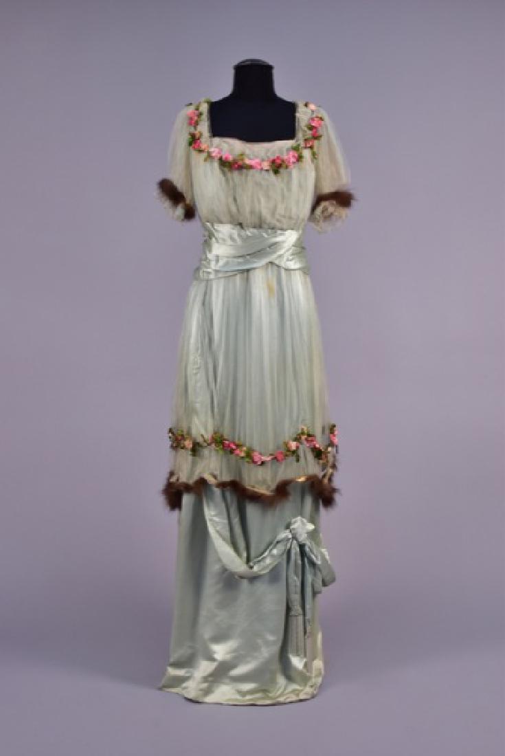 LEONARD & O'NEIL GOWN with SILK FLOWERS, EARLY 20th C.: Pale blue silk charmeuse having short sleeve tulle bodice overlay and overskirt decorated with pink and green silk flowers, neckline edged in paste jewels, sleeve and overskirt having mink hem, pleate