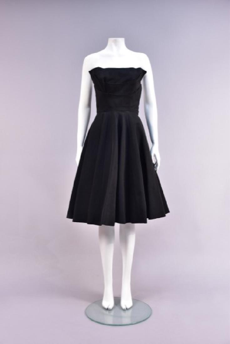 JEAN PATOU STRAPLESS SILK COCKTAIL DRESS, 1950s: Black bengaline having unusual boned bodice with extended straight-cut front panel behind two overlapping curved layers, set-in waist, circle skirt pieced in nine panels backed in a wide synthetic hor