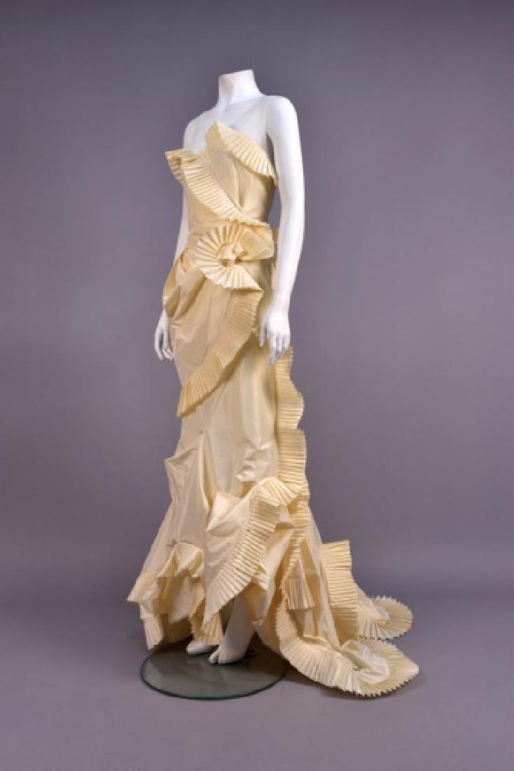 CHRISTIAN DIOR ASYMMETRICAL ORAGAMI GOWN, 2006: Vanilla silk blend taffeta having surplice bodice with tulle above self pleated trim, set-in waist, trained skirt with complex folds and draping having pleated swags, flower at waist. Lot includes Dio