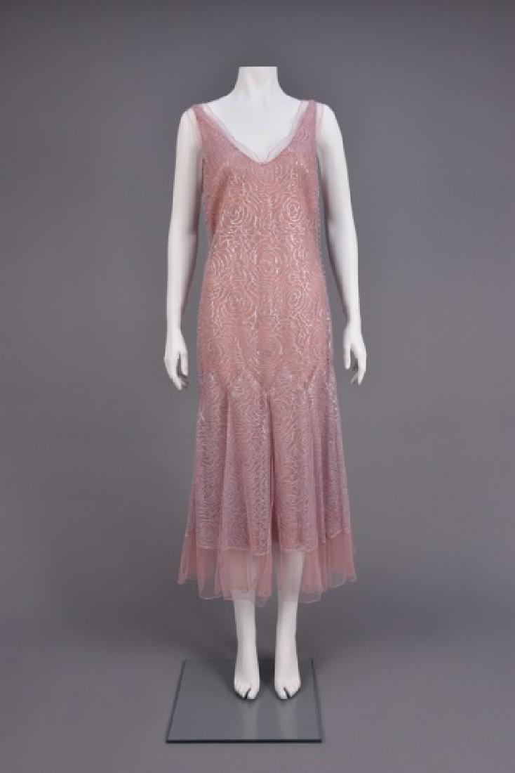 JOHN GALLIANO VINTAGE-INSPIRED METALLIC LACE DRESS: Silver metallic lace over pink silk chiffon, sleeveless with V-neck edged in tulle, the left side having faux self button & loop closures, dropped waist, A-line skirt with applied floating panels havi