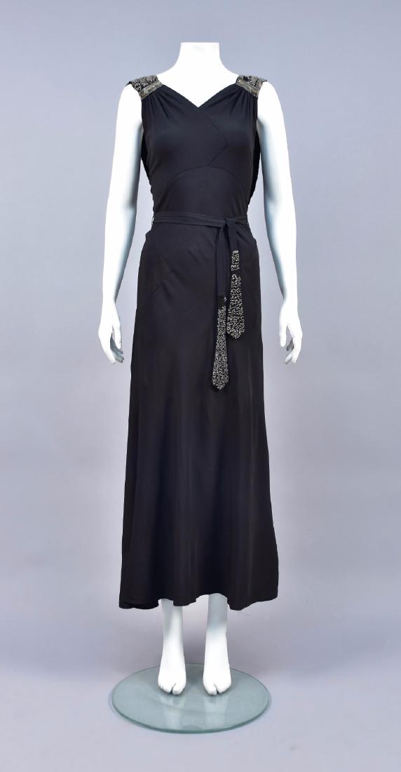 BIAS-CUT GOWN with BEADED DECORATION, 1930s: Black crepe with V-neck bodice having high curved waistline ruched into shoulder, scoop back with floating drape and bands of crystal bugle beads, shoulder having cushion-cut paillettes, self belt bea