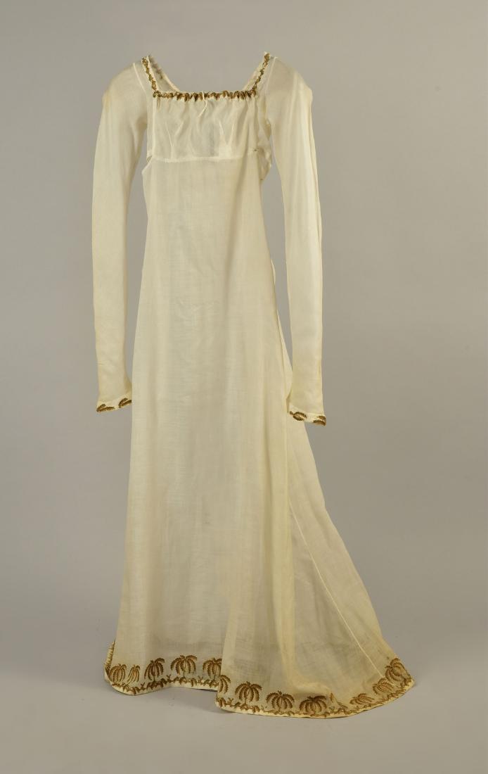 UNUSUAL MUSLIN DRESS with PALM TREE EMBROIDERY, 1805: Transparent white cotton with fall-open bodice and long sleeve, having tambour embroidered palm leaves in brown and green decorating the neckline and cuff, slightly trained skirt with a border of palm