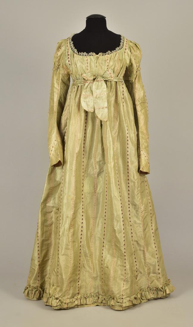 FRENCH STRIPED SILK GOWN, 1780s, RESTYLED c. 1815: Sage green taffeta with a cream, pink and brown ribbon stripe having empire bodice, rounded neckline trimmed with lace, long fitted sleeve with puffed shoulder and lace band at cuff, front closure wit