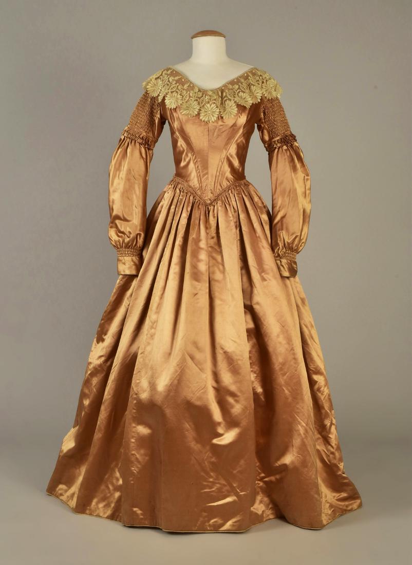 SATIN GOWN with DETACHABLE SLEEVES, 1839: Pink champagne silk having boned bodice with wide V-neck trimmed in blonde lace, the long sleeve is detachable at the shirred and ruffled collar, shirred above the cuff, front point with double row of