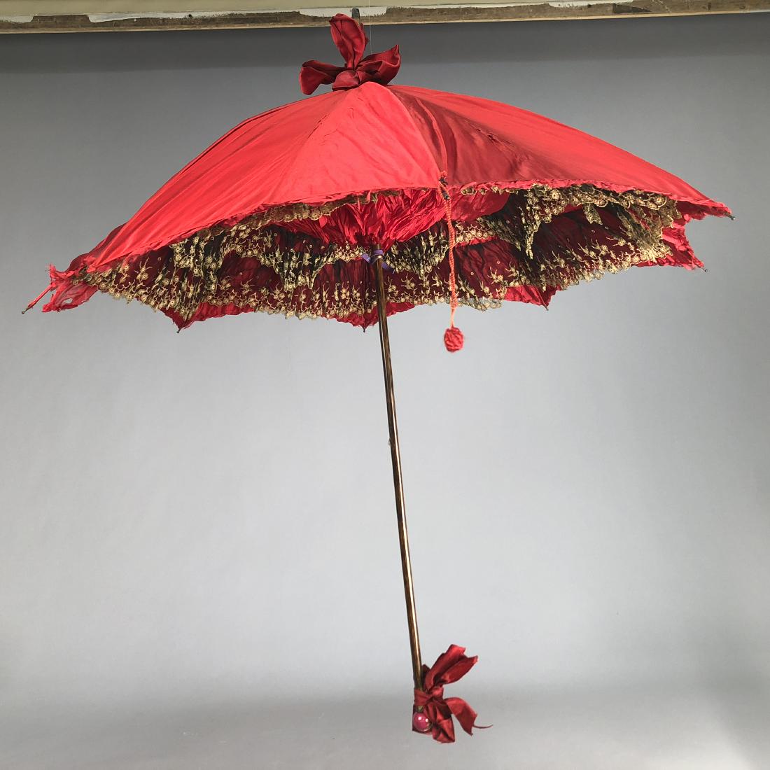 SATIN PARASOL with INTERIOR of BLACK and WHITE LACE,: Crimson satin with painted wood handle with Dresden porcelain end, decorated with silk bows, lined in crimson chiffon having ruffles of black chiffon embroidered with cream lace, tag indicates purchas