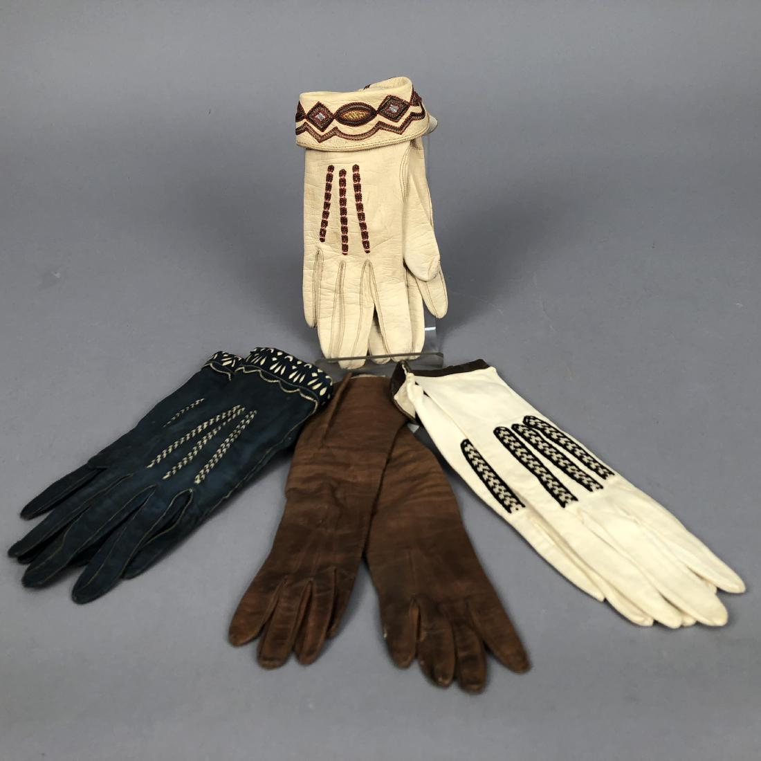 THREE PAIR DECORATED LEATHER GLOVES, c. 1920: All with applied braid: One bone having turn-back cuff with tambour embroidery inset with silver and gold leather; one pair white with black trim; one pair blue with pierced and scalloped cuff with wh