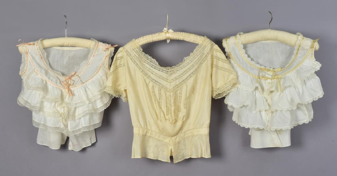 LOT of SIX LADIES' FANCY WHITES, 1900-1915: Two white cotton camisoles with lace-trimmed ruffles and silk ribbon, (tiny spot); one silk crepe de chine camisole with sleeves having lace bands, tucks, and fancy monogram, (lacking silk tie). Three