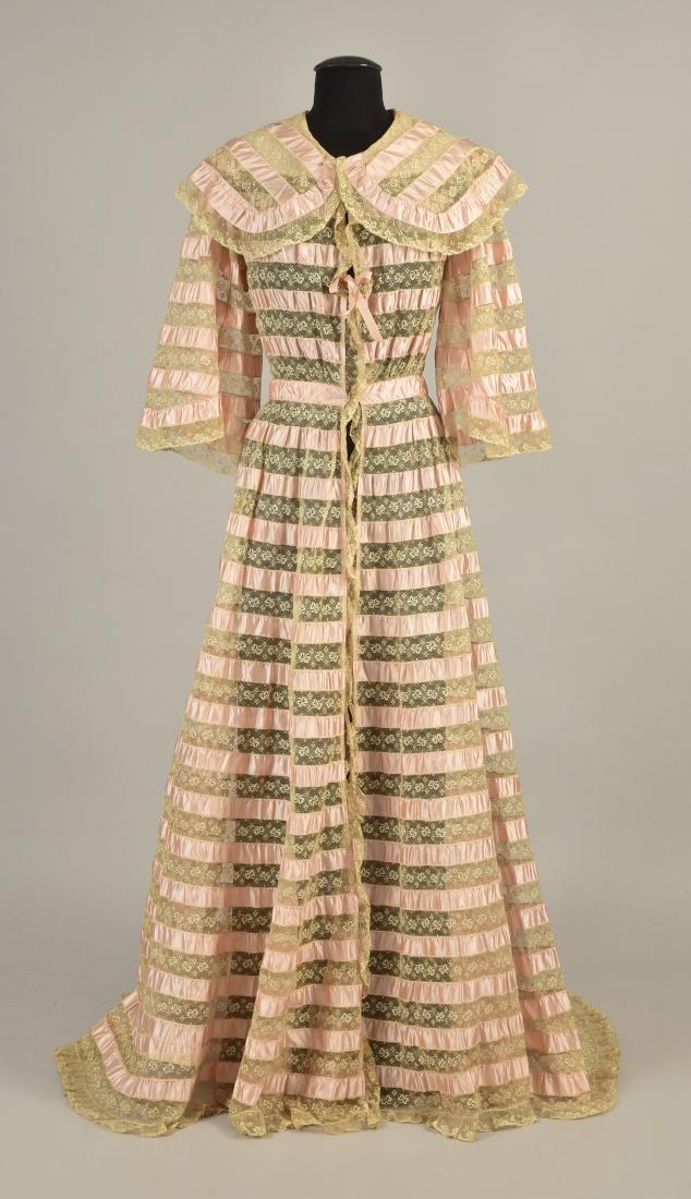 TRAINED RIBBON and LACE DRESSING GOWN, 1900: Alternating bands of pink satin ribbon and embroidered net with repeating bowknots, wide, rounded collar, three-quarter bell sleeve, full skirt with small train, hook & eye closures and single ribbon 