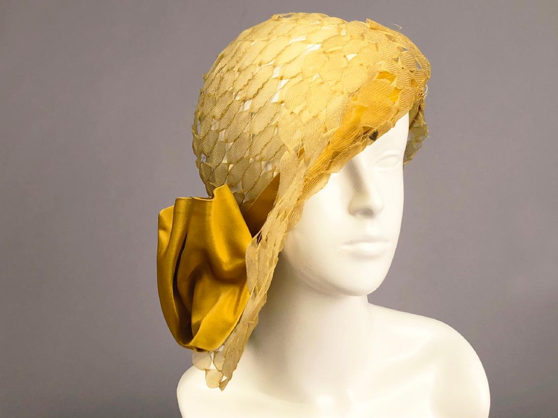 PARIS LABEL WIDE-BRIM HORSEHAIR CLOCHE, c. 1930: Summer hat of twisted golden horsehair ribbons having asymmetrical, wide, turned-up brim and gold satin band with bow, unlined, grosgrain ribbon band, label "Copy of Agnes Modes, 6 Rue St. Florentin. 