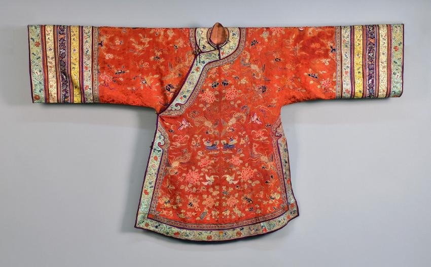CHINESE SILK and METALLIC EMBROIDERED ROBE, EARLY 20th: Cinnabar silk with a woven tone-on-tone floral, lavishly embroidered in polychrome silk forbidden stitch and satin stitch with couched gold threads depicting birds, flowers, dogs, butterflies and Budd