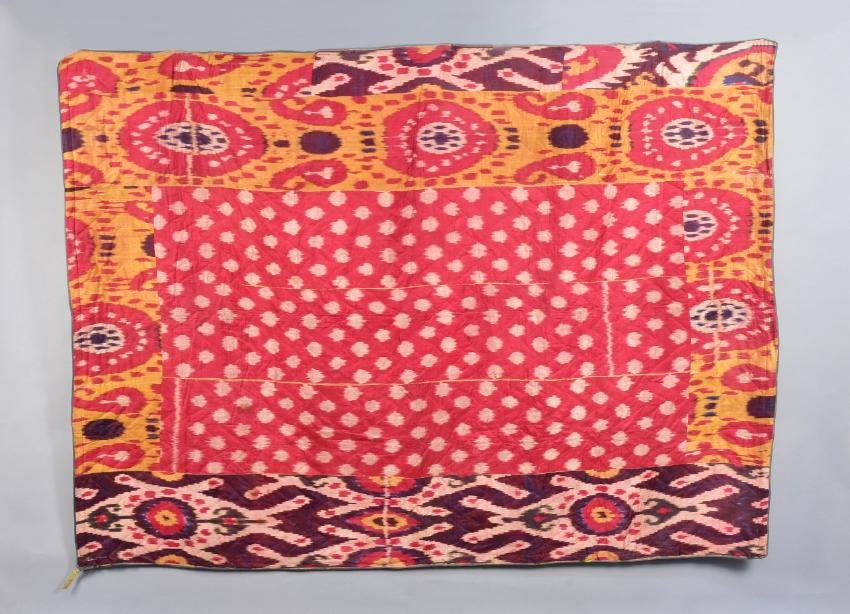 SILK IKAT BEDCOVER, CENTRAL ASIA, 20th C: Quilted and filled bedcover having six panels in three different designs. The central design of white dots on deep pink field, surrounded on all sides by narrow panels in purple, yellow, red and black