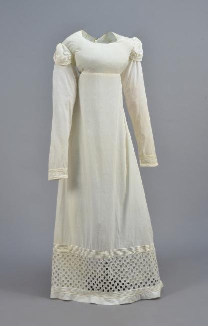 YOUNG GIRLS WHITE COTTON DRESS, AMERICAN, 1800 - 1825: High-waisted with long sleeve under shoulder cap cinched with button & loop, trimmed with narrow bands of rouleaux, having eyelet at the wrist, wide band of cutwork between bands of rouleaux at hem, t