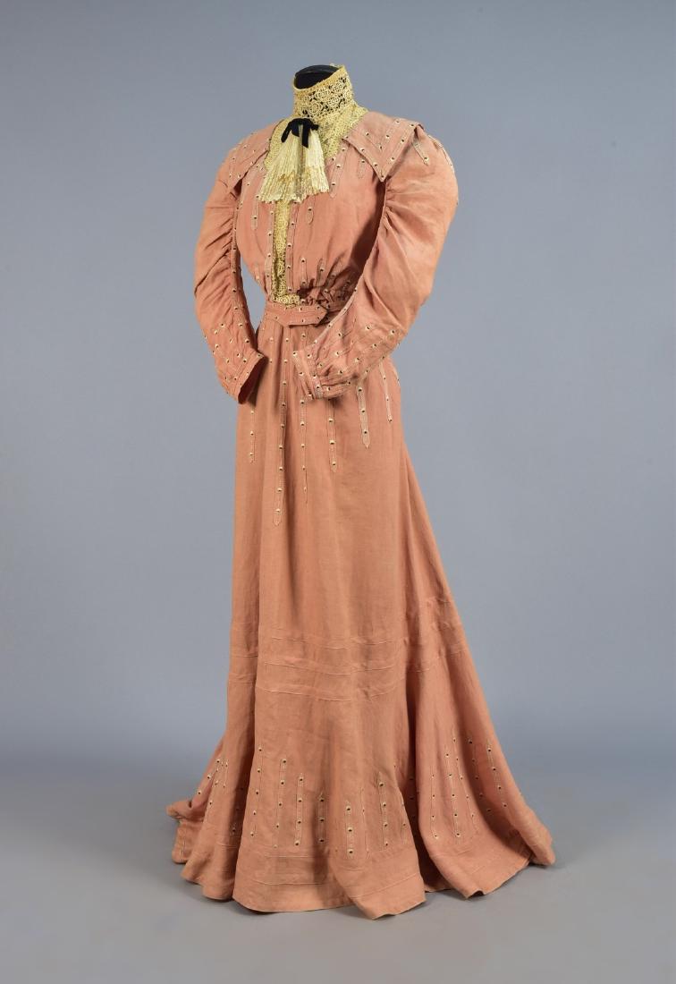 COTTON AFTERNOON GOWN with APPLIQUE and EMBROIDERY, c.: Dusty pink linen weave appliquÃ©d with narrow self bands embroidered in black and white, long sleeve bodice having high-neck lace insert, cuff and center band beneath an embroidered net frill, self 
