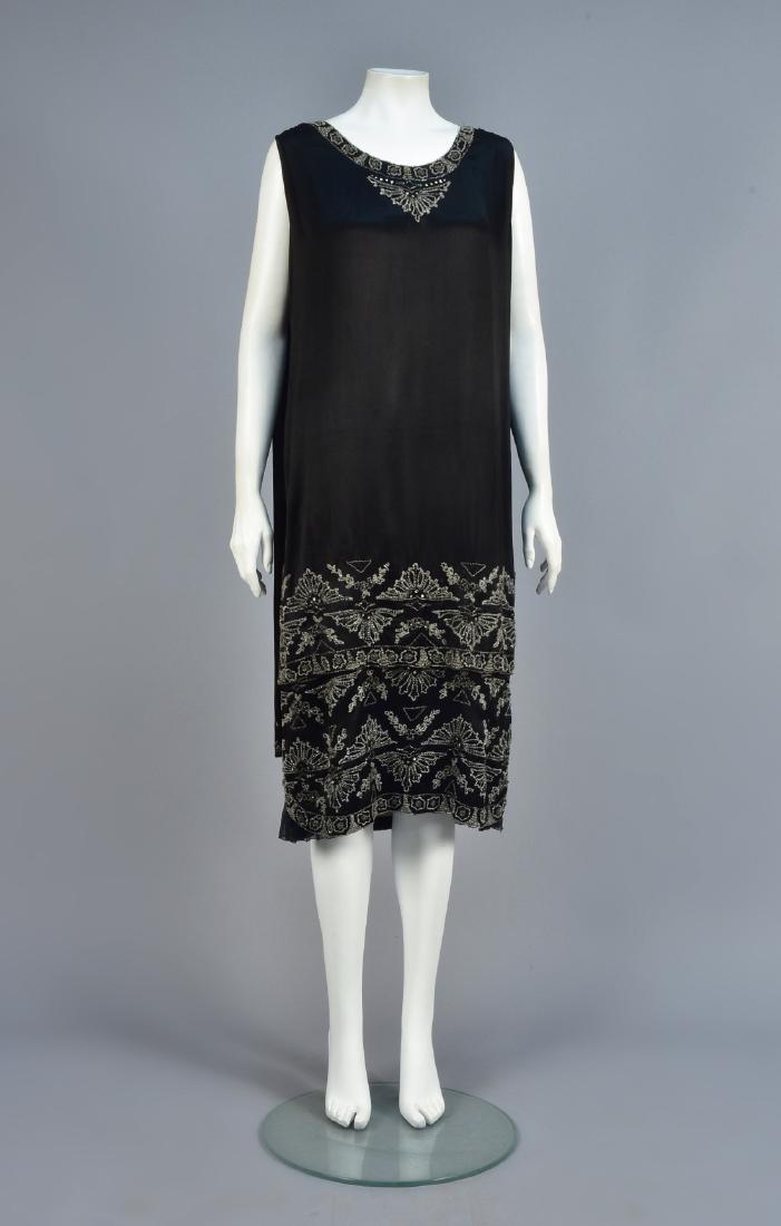CRYSTAL-BEADED SILK DRESS, 1920s: Sleeveless black satin having over-tunic with shoulder streamers decorated at the neck and hem in a geometric pattern with rhinestones and prong-set paste jewels, pink silk underdress having a lower s