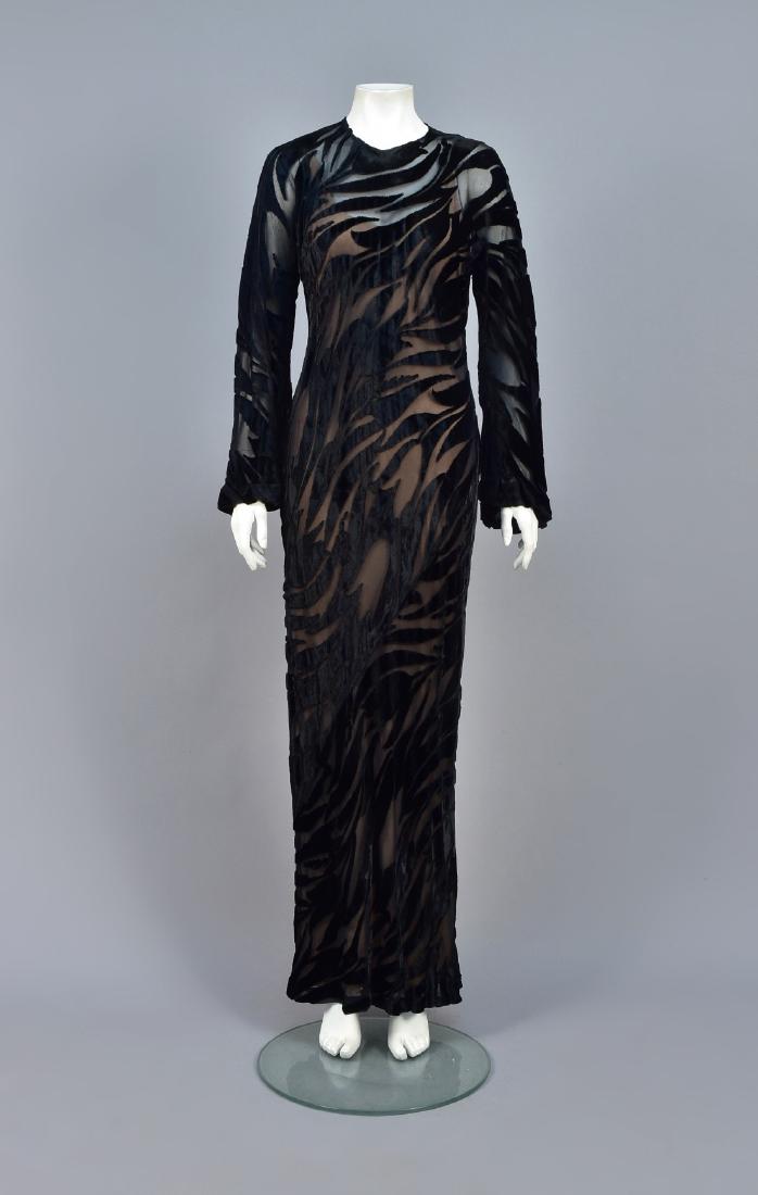 HALSTON BURNOUT VELVET EVENING GOWN, 1977: Black velvet cut to chiffon in a tulip pattern, having long bell sleeve, keyhole back, and sleeveless nude underdress, labeled. Pictured on page 187 of "Halston an American Original" by Elaine Gross a