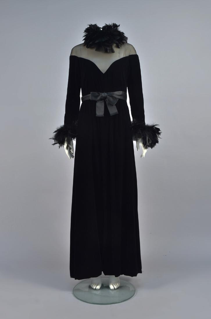 OSCAR de la RENTA VELVET GOWN with FEATHERS, 1970s: Black velvet with a triangular gauze upper bodice and long sleeve with rooster feather cuff, wide A-line skirt slightly gathered at waist, satin belt with bow, labeled. B-36, W-28, L-60. (Some feather