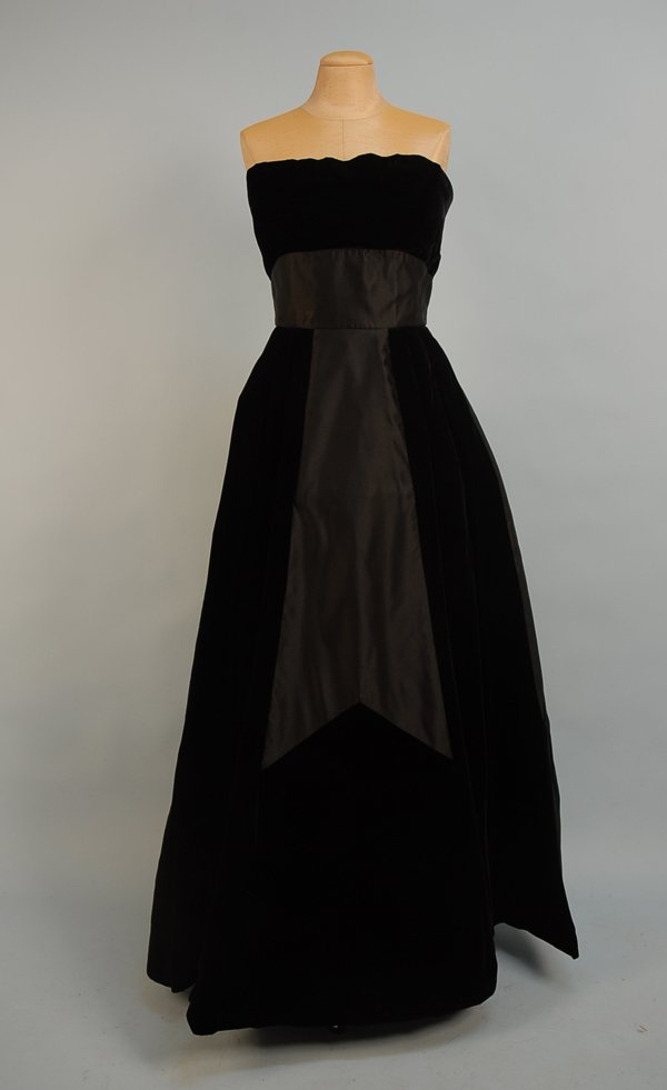 OLEG CASSINI STRAPLESS VELVET EVENING GOWN, MID 20: OLEG CASSINI STRAPLESS VELVET EVENING GOWN, MID 20th C Black velvet with boned bodice having black silk band, full skirt stiffened with heavy interfacing, inset with wide panels of black silk having i