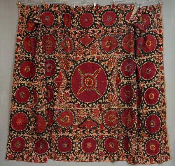 TASHKENT SUSANI, 20th C. Natural cotton decorated w: TASHKENT SUSANI, 20th C. Natural cotton decorated with silk in cranberry with purple, orange, gold, green and blue. 82 x 123. Some stains and repairs, corners damaged, good.