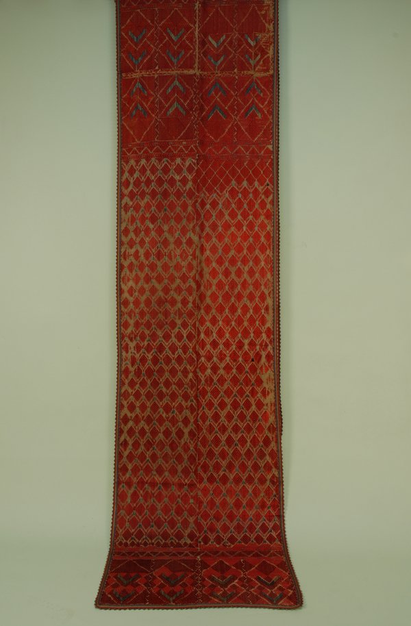 PERSIAN EMBROIDERED LONG PANEL, EARLY 20th C. Two j: PERSIAN EMBROIDERED LONG PANEL, EARLY 20th C. Two joined narrow cotton lengths embroidered in red silk stylized leaf repeat on natural cotton, wide end borders in large diamond pattern with blue chevr