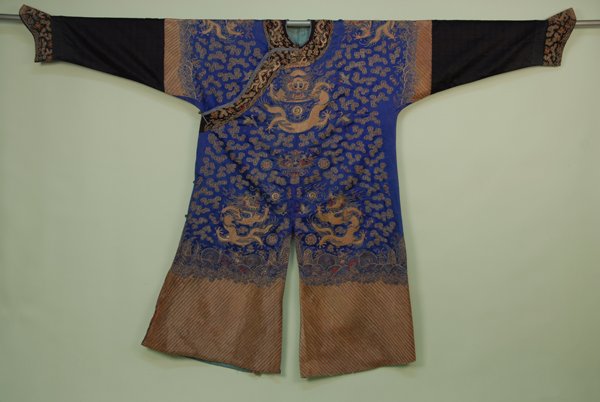 CHINESE DRAGON ROBE, c. 1890. Blue silk with couche: CHINESE DRAGON ROBE, c. 1890. Blue silk with couched metallic embroidery having eight dragons, cloud bands, birds, symbols, rockwork and sylized wave band over metallic rainbow border, black silk slee