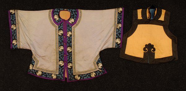 TWO CHINESE SILK GARMENTS, 1920's. Gold vest with : TWO CHINESE SILK GARMENTS, 1920's. Gold vest with applied black silk borders, high Mandarin collar having knotted cord button and frog closure, body of vest with eight double frog closures requiring b