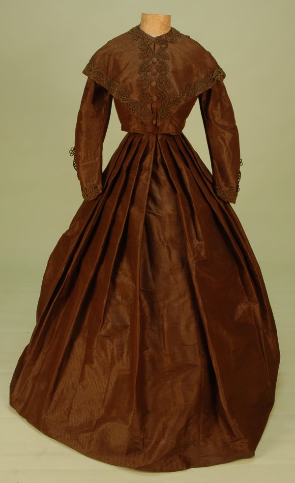RIBBED SILK VISITING DRESS with PELERINE, c. 1865.: RIBBED SILK VISITING DRESS with PELERINE, c. 1865. 3-piece chestnut satin having a woven gold horizontal rib, bodice with silk covered faux front buttons over hook & eye closures, straight bottom, sle