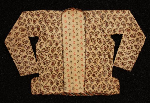 PERSIAN PRINTED COTTON JACKET, QAJAR ERA. White po: PERSIAN PRINTED COTTON JACKET, QAJAR ERA. White polished cotton in an overall pattern of small floral botehs in red, green, blue and black, having V-neck with narrow stand collar at back of neck and a