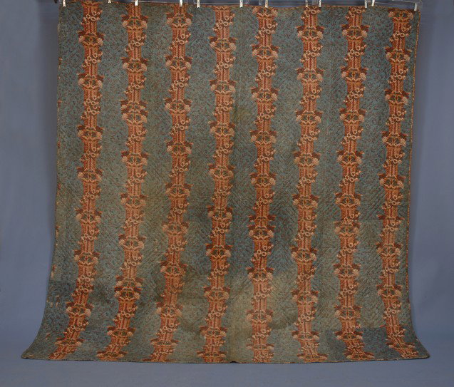 WHOLE CLOTH QUILT, 19th C. Cotton printed with colu: WHOLE CLOTH QUILT, 19th C. Cotton printed with columns, floral garlands and grape clusters on an overall repeat of meandering foliage in cream and brick red on slate blue ground, backed with a printed