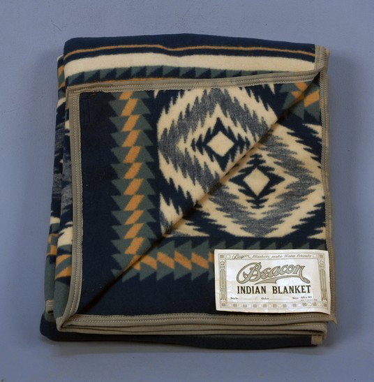 DEADSTOCK BEACON INDIAN BLANKET, 1930's-1940's. Sha: DEADSTOCK BEACON INDIAN BLANKET, 1930's-1940's. Shades of blue with cream and sand, having original sewn on paper label and corner sewn back for display. 66 x 88. (Paper label has creases) blanket pri