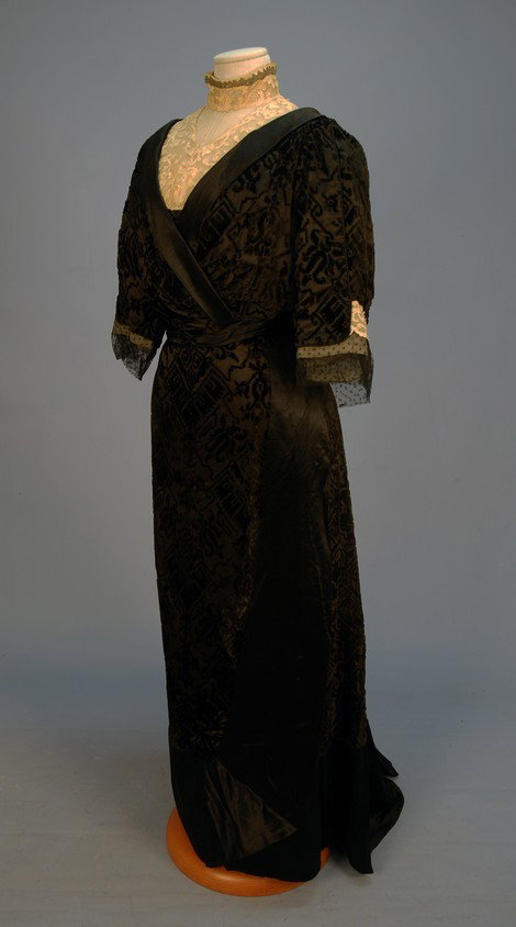 CUT VELVET and SATIN EDWARDIAN GOWN with NEEDLE LA: CUT VELVET and SATIN EDWARDIAN GOWN with NEEDLE LACE TRIM. 2-piece black silk, the wrap front bodice having lace high neck insert and elbow length sleeve, wrap front skirt with wide satin edge and hem
