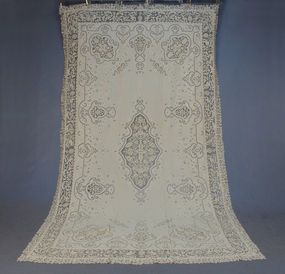 LINEN TABLECLOTH with CUTWORK, EMBROIDERY and LACE: LINEN TABLECLOTH with CUTWORK, EMBROIDERY and LACE, c. 1930. White with central reserve and cartouches filled with needle lace, having a border band of figural lace with running nymphs. 70 x 108. (Sma