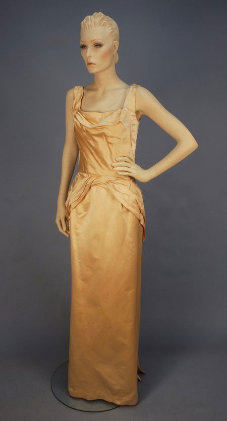 CEIL CHAPMAN SATIN EVENING GOWN, MID 20th C. Sleev: CEIL CHAPMAN SATIN EVENING GOWN, MID 20th C. Sleeveless ivory silk with draped neckline and twisted fabric at waist fanning out over hips, nipped and pleated at back, back zipper. Label "Ceil Chapman"