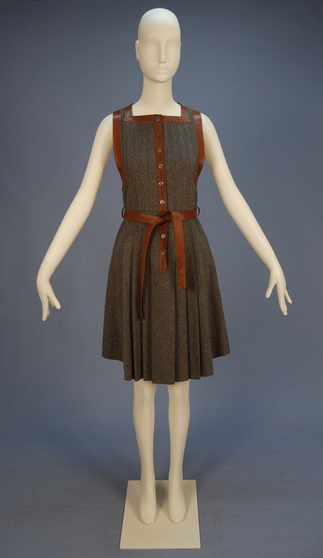 JEAN MUIR LEATHER TRIMMED WOOL PINAFORE DRESS, EAR: JEAN MUIR LEATHER TRIMMED WOOL PINAFORE DRESS, EARLY 1970's. Sleeveless grey wool having square neckline and long armhole both trimmed in brown topstitched leather along with the front button placket 