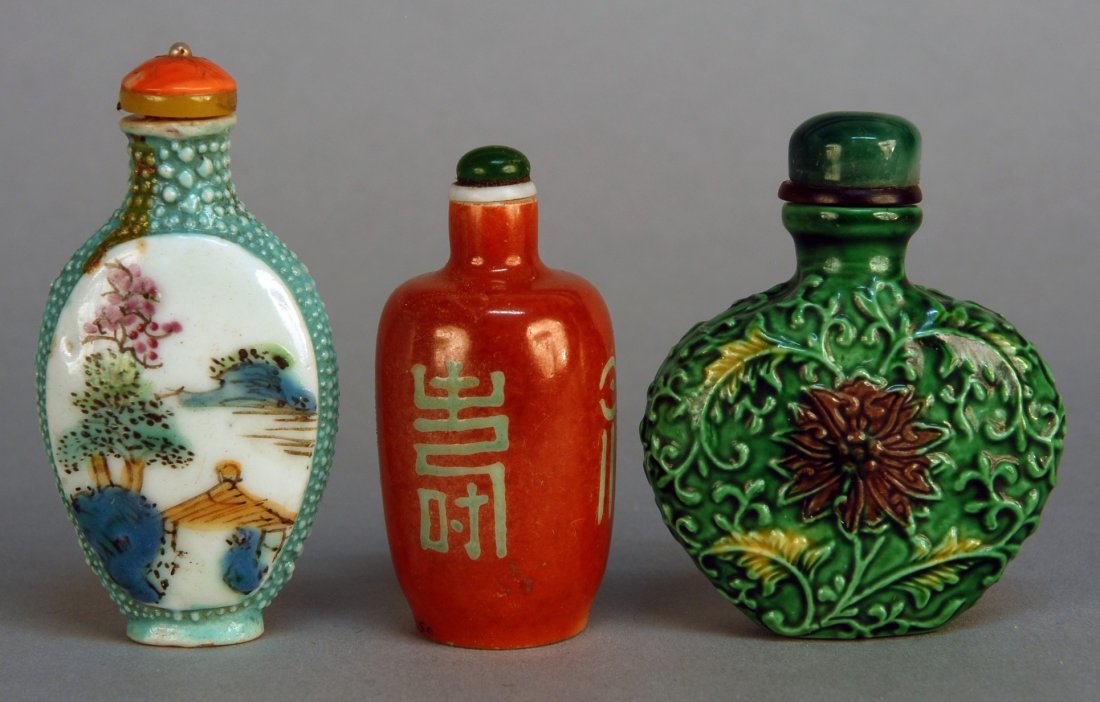 THREE CHINESE PORCELAIN SNUFF BOTTLES, 19th C. One: THREE CHINESE PORCELAIN SNUFF BOTTLES, 19th C. One green with incised chrysanthemum. One cinnabar glazed with happiness characters. One with simulated shagreen and reserves with landscapes and lover's