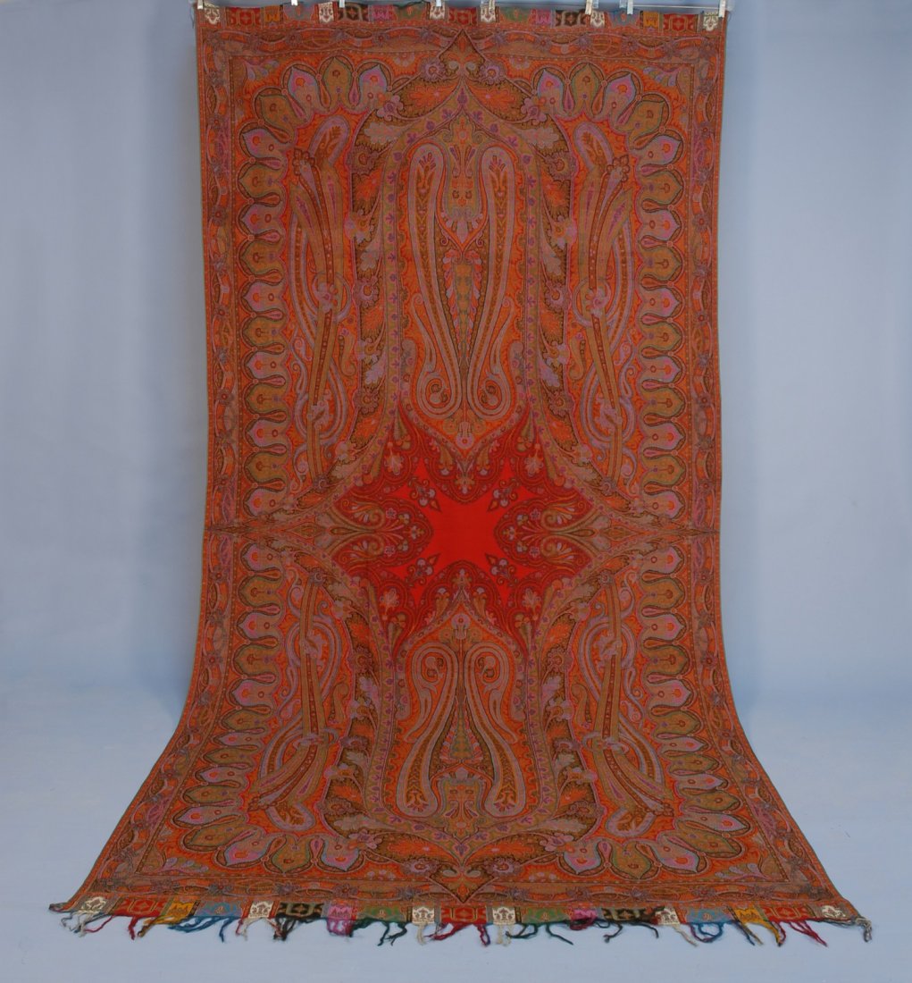 WOOL PAISLEY SHAWL, 19th C. Long rectangle with "X: WOOL PAISLEY SHAWL, 19th C. Long rectangle with "X" shaped center in bright pink, blue, green, red, orange and brown, having interlocking paisleys and tabbed border, 64 x 128, excellent.