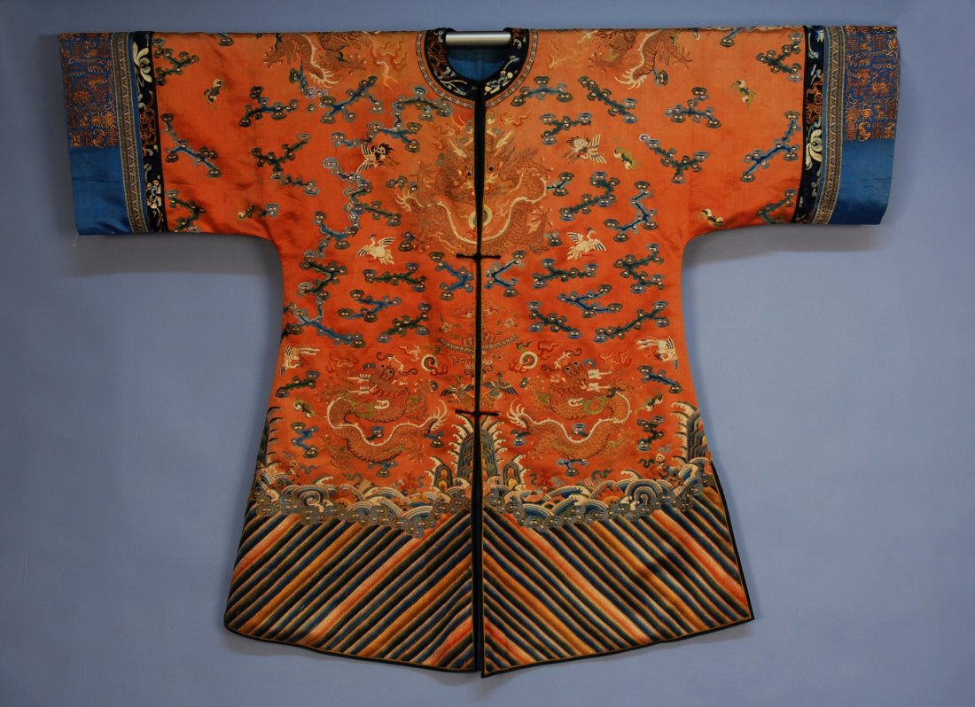 CHINESE SILK EMBROIDERED DRAGON SURCOAT, 19th C. C: CHINESE SILK EMBROIDERED DRAGON SURCOAT, 19th C. Copper satin having eight gold metallic dragons with finely worked scales surrounded by bats and birds amid clouds, wave and rainbow border, blue satin