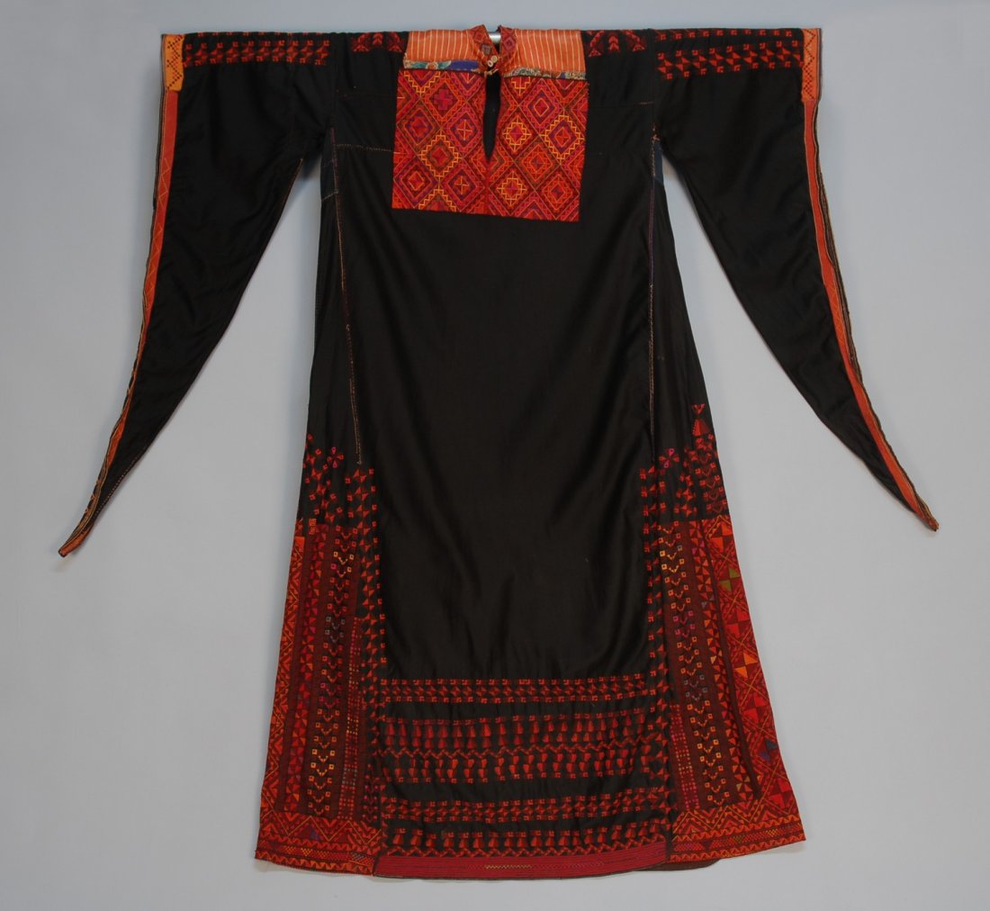 BEDOUIN CROSS STITCH EMBROIDERED ROBE, 20th C. Bla: BEDOUIN CROSS STITCH EMBROIDERED ROBE, 20th C. Black cotton twill with orange striped satin yoke, the front and stand collar having applied geometric embroidery, wizard sleeve, side gores and hem heav