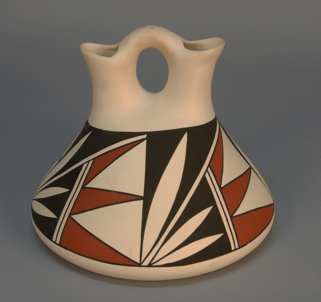 ACOMA POTTERY WEDDING VASE, c. 1960's. Squat taper: ACOMA POTTERY WEDDING VASE, c. 1960's. Squat tapering flask form with red, white and black decoration of foliage and geometric forms, loop ring handle joining two spouts signed "P. Estevan Acoma, NM."