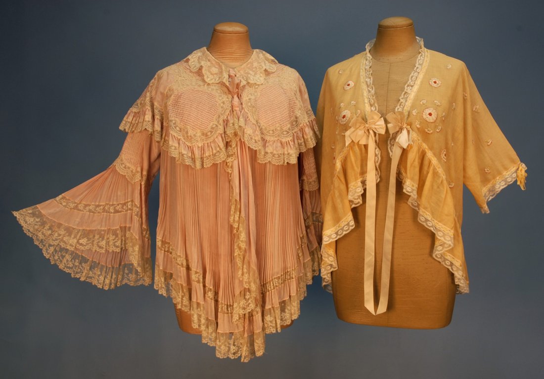 TWO LADIES' DRESSING or BED JACKETS, EARLY 20th C.: TWO LADIES' DRESSING or BED JACKETS, EARLY 20th C. One pleated pink silk with bell sleeve, tucked capelet and lace trim. One pale gold cotton crepe having red and white embroidery with ribbon and lace