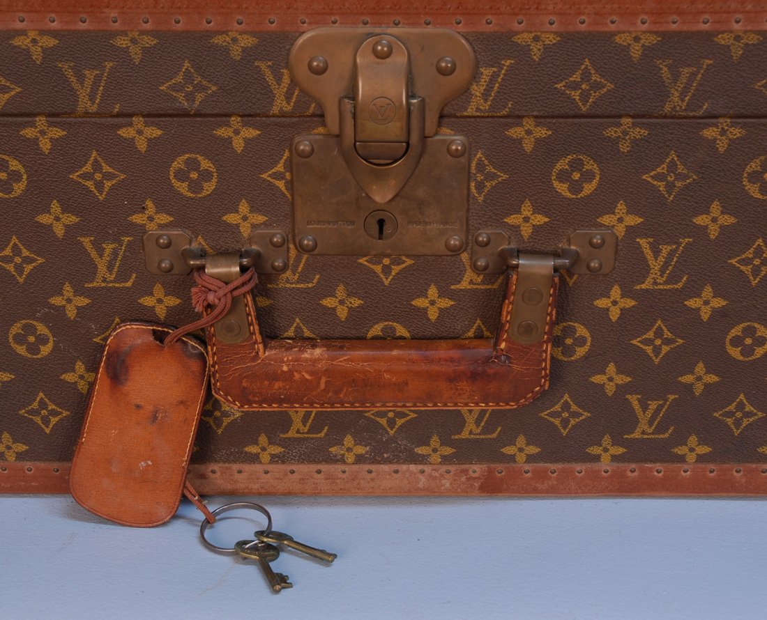 A VINTAGE LOUIS VUITTON HARD SUITCASE. Partial lea: A VINTAGE LOUIS VUITTON HARD SUITCASE. Partial leather trim and brass corners with "LV" stenciled logo surface, two original keys. 31 x 21 x 10. Very good.