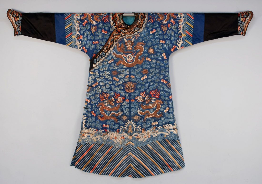 CHINESE SILK EMBROIDERED DRAGON ROBE, 19th C.: Blue silk nine-dragon robe having three dragons front an back, one on each horse hoof cuffed sleeve and one under front closure. Each worked in couched metallic threads, deep "li shui" hem. 82 x 58. (
