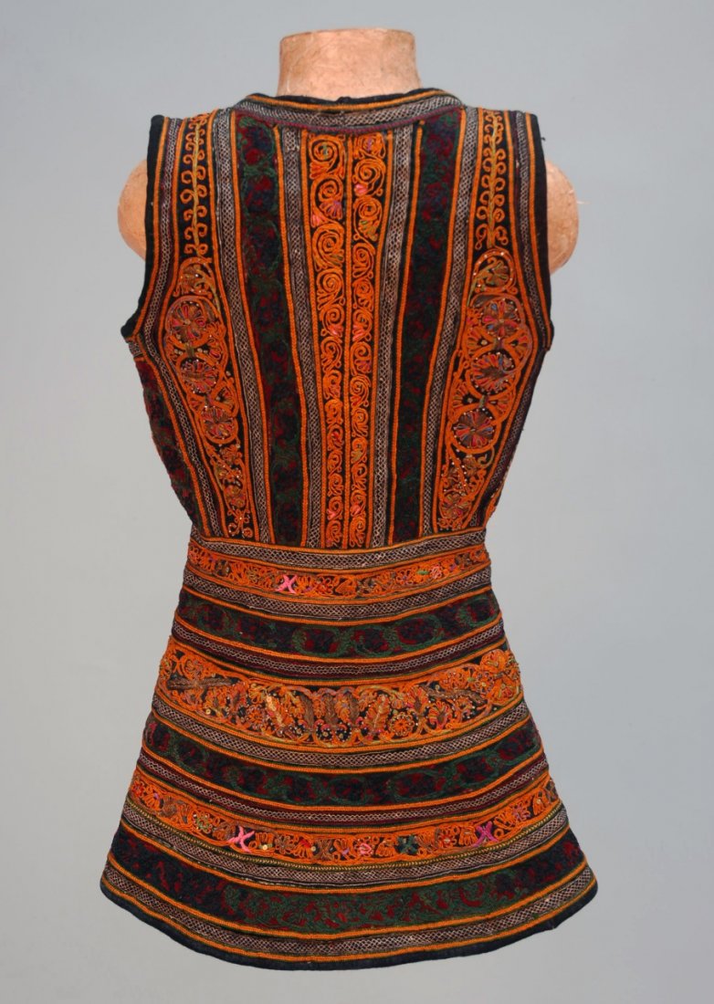 TURKISH APPLIQUED and EMBROIDERED VEST, 20th C.: Heavy cream wool decorated allover with burgundy, green and navy velvet bands embroidered in orange, green and blue accented with pink, metallic gold and tiny beads. Small size, probably for a child, 